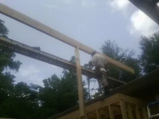 Carpenter setting a ridge beam over a new addition frame — Ice Dam Removal by Roofing Brothers in Needville