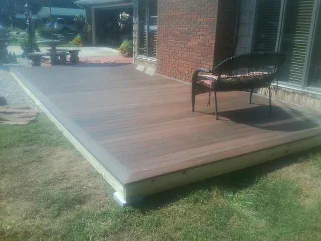 New wood deck and wicker chair beside a brick house in Needville