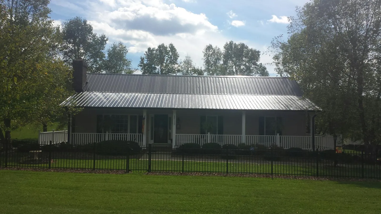 Gray metal roof on a brick ranch with a full width front porch — Gutter Guard Installation work by our crew in Needville