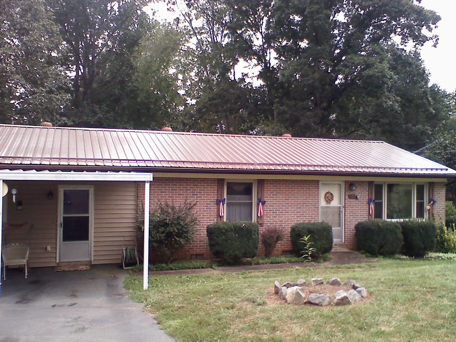 Bronze metal roof and carport on a brick ranch home — Roof Repair work by our crew in Needville