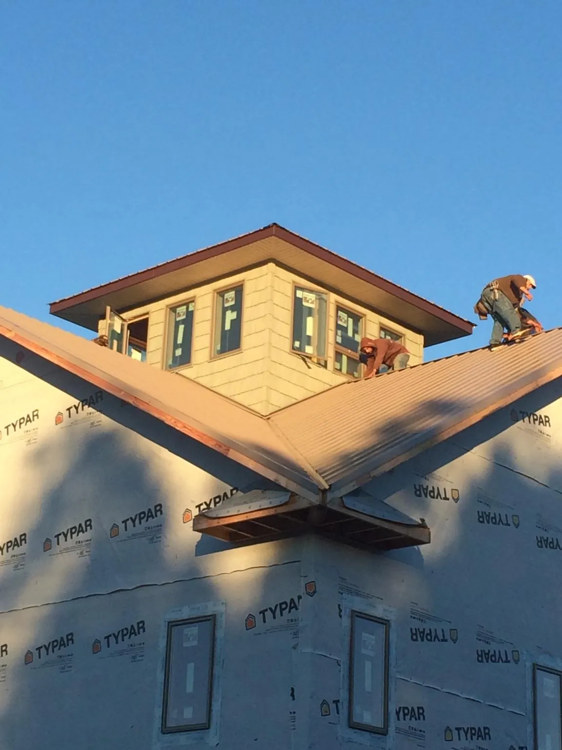 Roofers working around a rooftop cupola on a new metal roof at sunset — Roof Waterproofing in Needville by Roofing Brothers